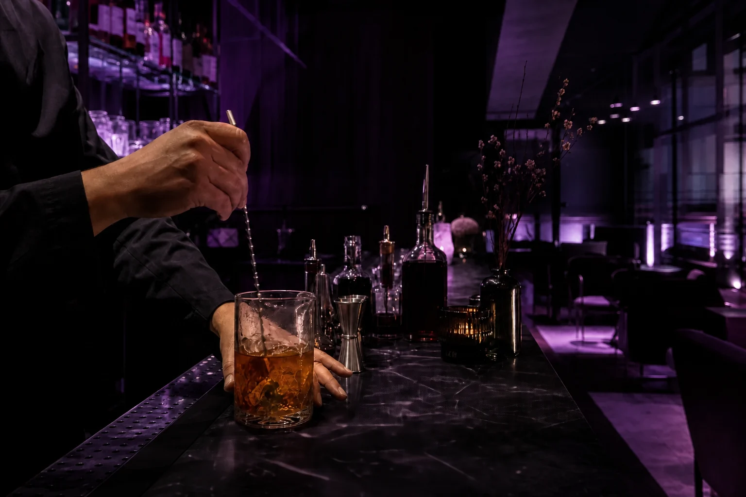 Barmen precizno priprema koktel za šankom